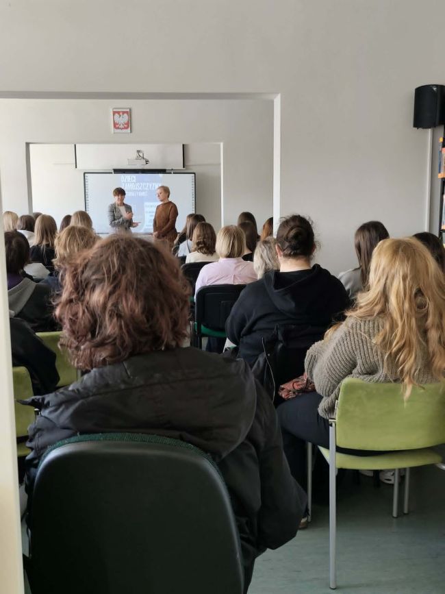 sala pełna ludzi, dwie kobiety przy tablicy multimedialnej;