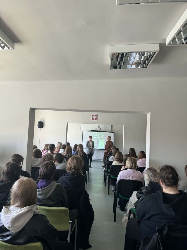 sala pełna ludzi, dwie kobiety przy tablicy multimedialnej;
