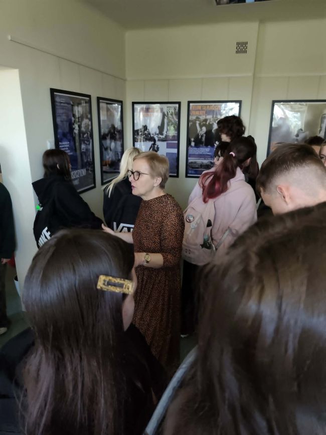 kobieta mówiąca do ludzi oglądających wystawę;