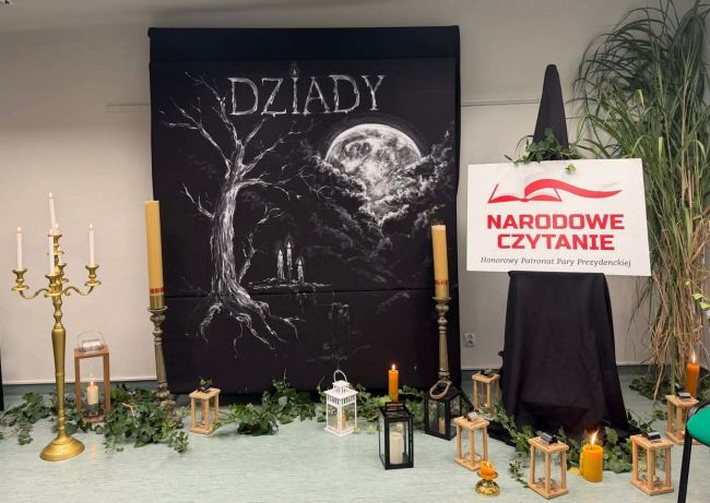 na pierwszym planie napis Dziady na czarnym tle, wokół świece i baner Narodowego Czytania