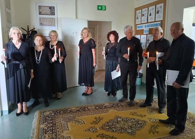 seniorzy trzymający w dłoniach zapalone świece