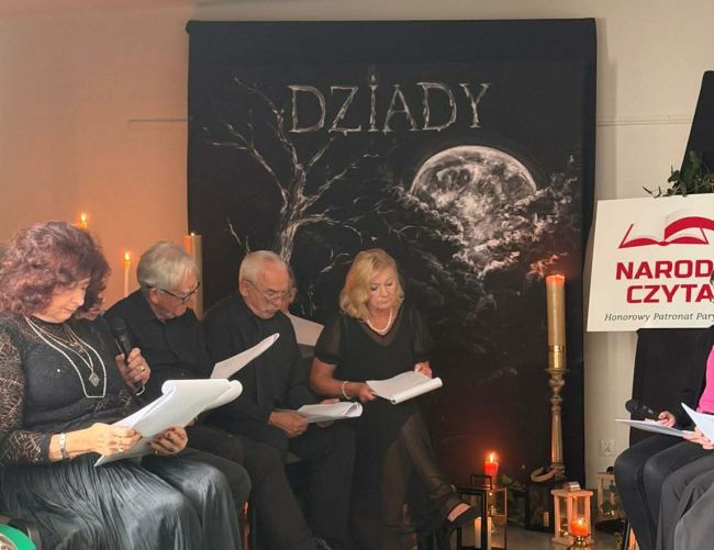 seniorzy siedzący pod napisem Dziady