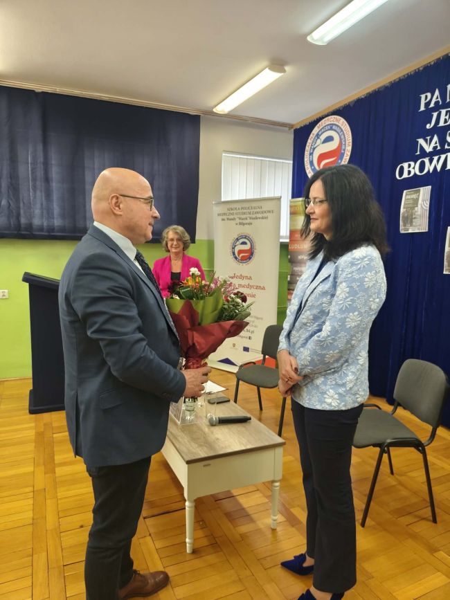 mężczyzna wręczający kobiecie bukiet kwiatów, w tle druga kobieta