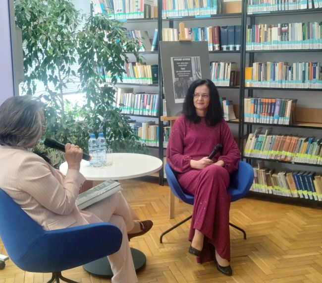 Zaproszeni goście siedzą w sali czytelni biblioteki