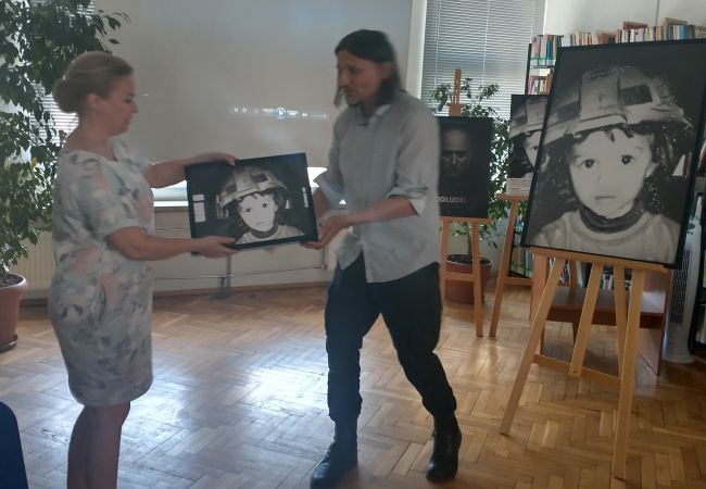 Autor wręcza kierownikowi biblioteki pamiątkową rycinę z książki.