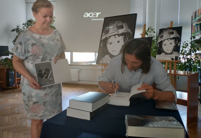  Autor podpisuje książkę kierownikowi biblioteki pedagogicznej.