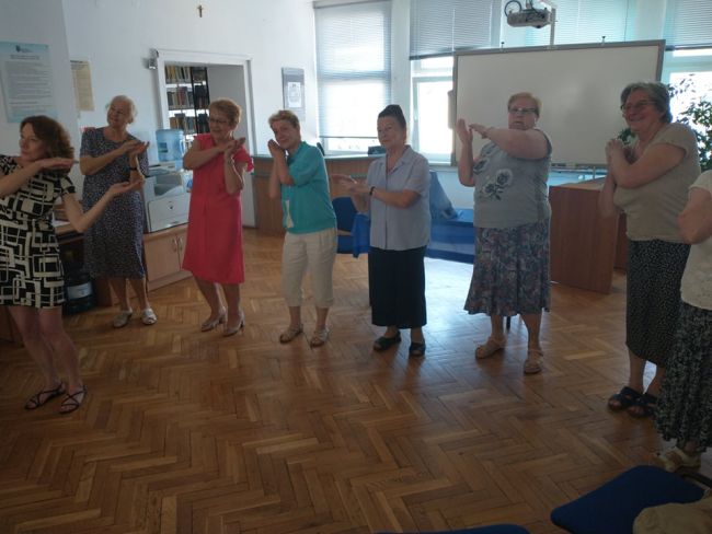 Biblioteka. Słuchacze Uniwersytetu Trzeciego Wieku uczestniczą w zabawie ruchowej