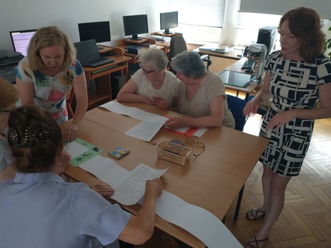 Biblioteka. Uczestnicy siedzą przy stolikach wykonując zadania zlecone przez nauczyciela bibliotekarza
