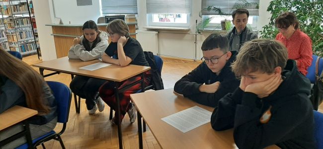 Uczniowie siedzą w ławkach. Nauczyciele bibliotekarze prowadzą zajęcia o Melchiorze Wańkowiczu – patronie roku 2024