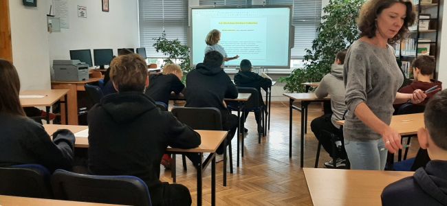 Uczniowie siedzą w ławkach. Nauczyciele bibliotekarze prowadzą zajęcia o Melchiorze Wańkowiczu – patronie roku 2024