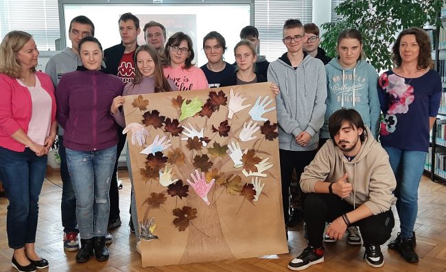 Zdjecie zbiorowe na zakonczenie zajęć. Uczniowie trzymają plakat samodzielnie wykonanego drzewa życia z jesiennych liści.