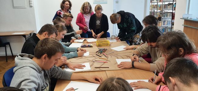 Uczniowie przy stoliku wykonyją pracę plastyczną – jesienne drzewo