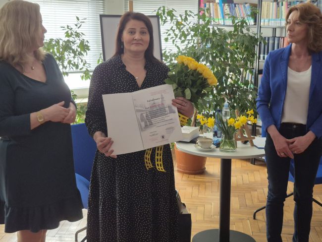 Kierownik biblioteki wraz z prowadzącą w trakcie wręczania autorce podziękowania za spotkanie.