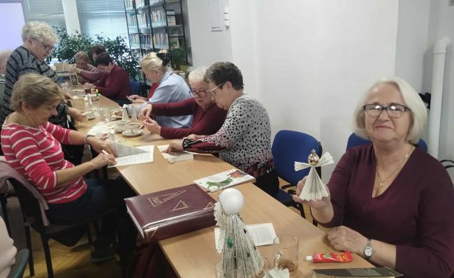 Uczestnicy warsztatów siedzą przy stołach i wykonują prace.