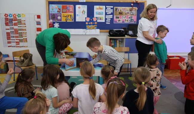 Dzieci uczestniczą w zabawie sensorycznej z magicznym pudełkiem, odgadują zwierzątka dotykiem.