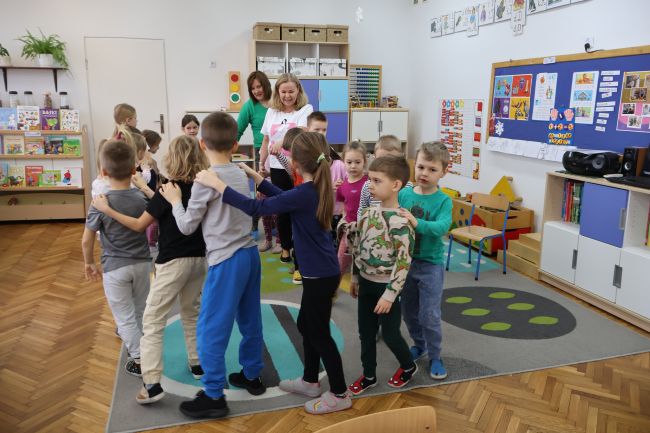 Nauczyciele prowadzą zabawę, przedszkolaki biegają po sali.