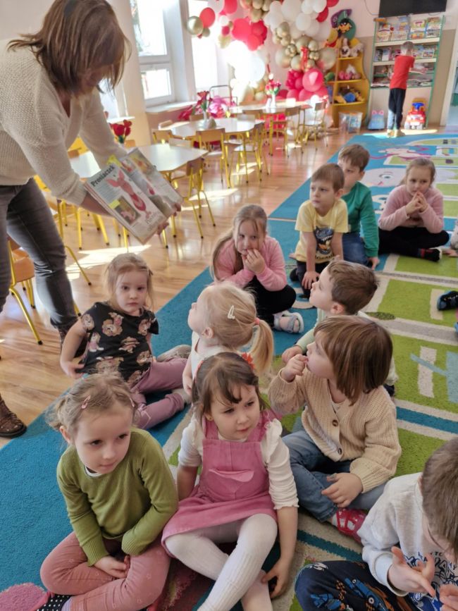 Prowadzący zajęcia pokazuje ilustracje w książce, dzieci słuchają i oglądają.