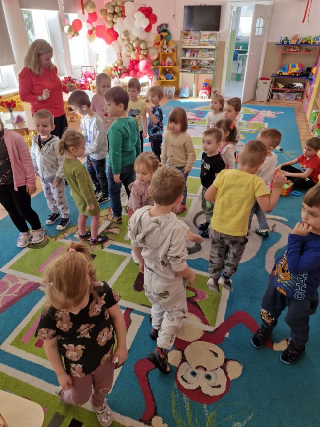 Nauczyciel prowadzi zabawę na dywanie, dzieci wykonują polecenia.