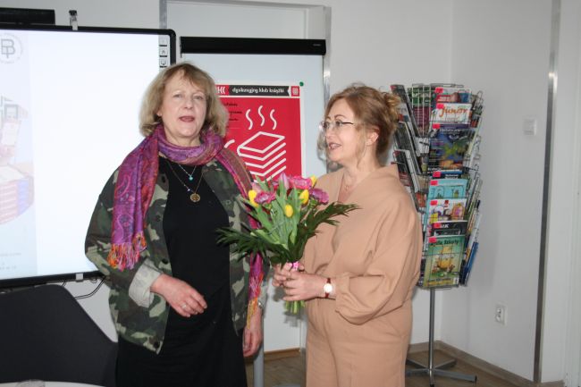 Zdjęcie pokazuje jak wicedyrektor Biblioteki Pedagogicznej wręcza bukiet kwiatów pisarce Teresie Monice Rudzkiej na zakończenie spotkania autorskiego.