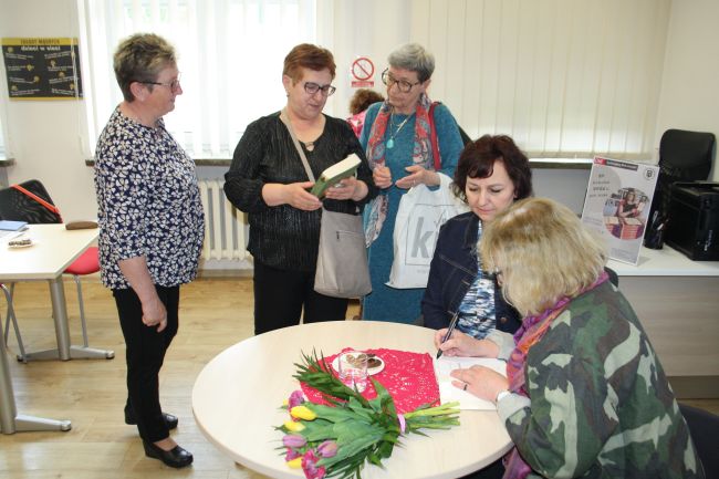 Na zdjęciu widać jak Teresa Monika Rudzka podpisuje swoje książki osobom zainteresowanym.