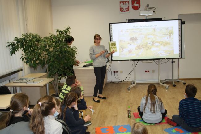 Na zdjęciu widać prowadzącą Agnieszkę Kowalczuk, która prezentuje książkę Alana Alexandra Milnego 