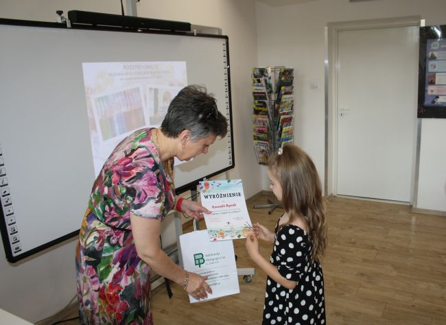 Laureatka konkursu Kornelia Rycak odbiera wyróżnienie z rąk dyrektora Biblioteki Pedagogicznej w Zamościu.