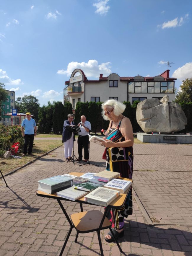 Na pierwszym planie kobieta przeglądająca książki