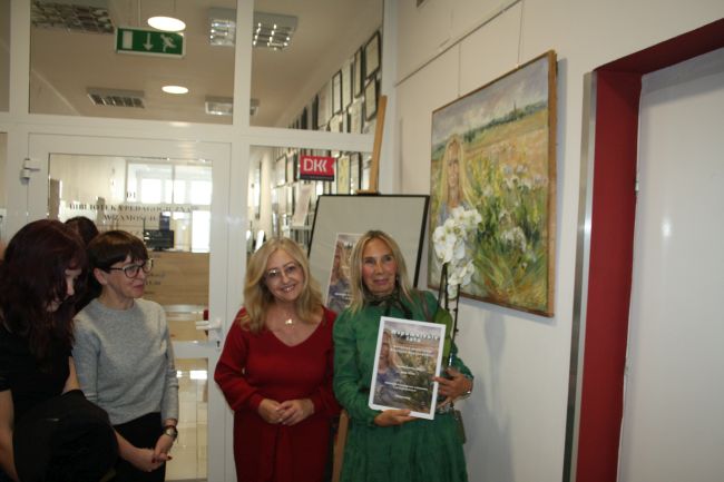 Autorka wystawy z pamiątkowym plakatem i kwiatem