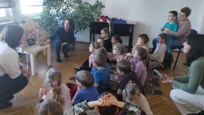 Przedszkolaki w trakcie słuchania opowiadania kamishibai „Noc w bibliotece”