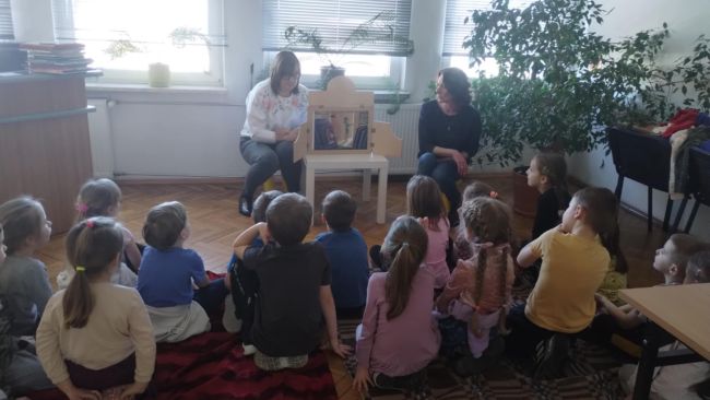 Przedszkolaki w trakcie słuchania opowiadania kamishibai „Noc w bibliotece”