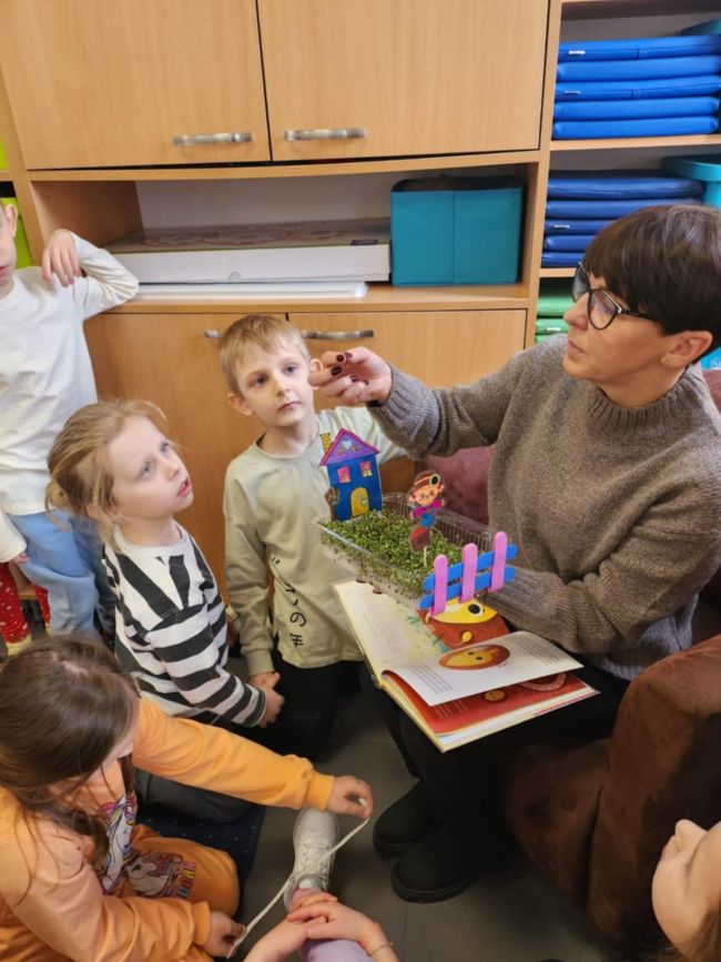 dzieci patrzą na pokazywane przez panią nasiona