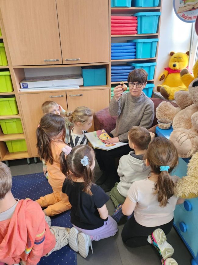 dzieci patrzą na pokazywaną przez panią cebulę