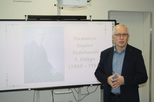 Prowadzący na tle prezentacji o Fudakowskim