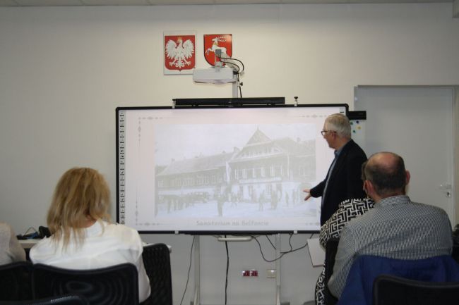 Prowadzący na tle prezentacji o Fudakowskim (sanatorium na Belfoncie)