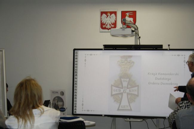 Prowadzący na tle prezentacji o Fudakowskim (odznaczenie duńskie)