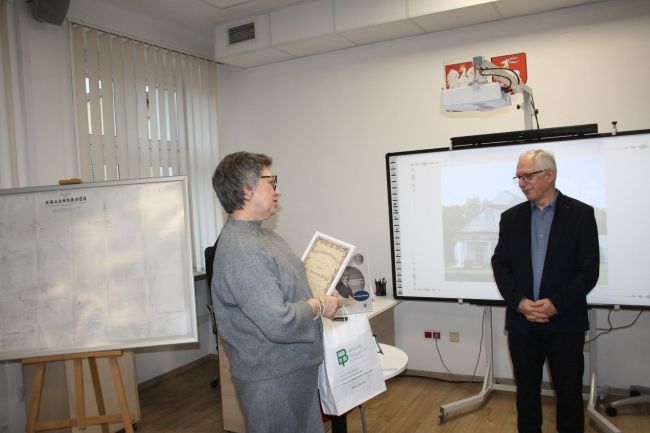Pani dyrektor wręcza prezent prowadzącemu w podziękowaniu za spotkanie