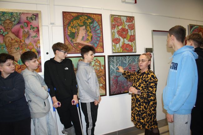 Magalena Cieplechowicz-Buczak omawia obraz z wystawy. Publiczność się przysłuchuje.