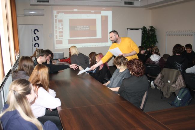 Łukasz Kot rozdaje uczniom ćwiczenia do wykonania.